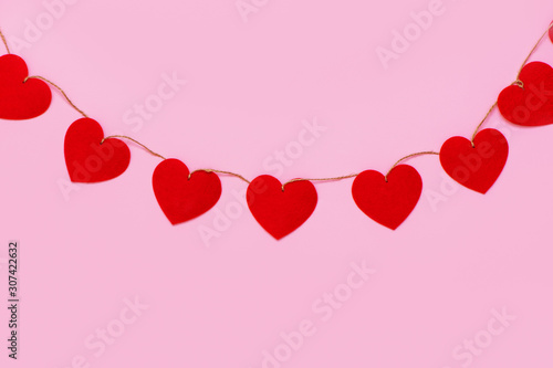 Hearts garland hanging on pink background.