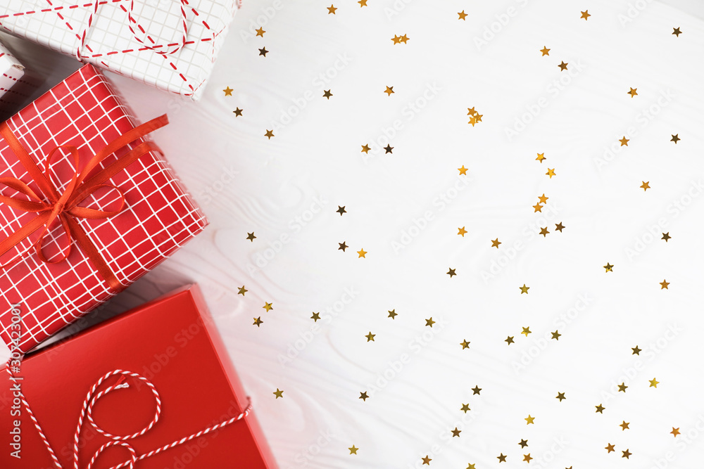 Festive gift boxes on white background with golden star confetti. Flat lay style. - obrazy, fototapety, plakaty 