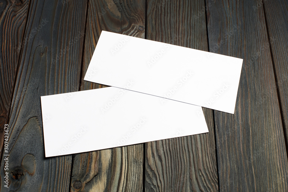 Two blank cards or papers (business cards, tickets, flyers, invitations, coupons, banknotes, etc.) on dark wooden background Two blank cards or papers (business cards, tickets, flyers, invitations, coupons, banknotes, etc.) on dark wooden background