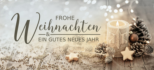 Christmas greeting card german text - Merry Christmas and happy new year - White burning candle with natural decoration on rustic light wood