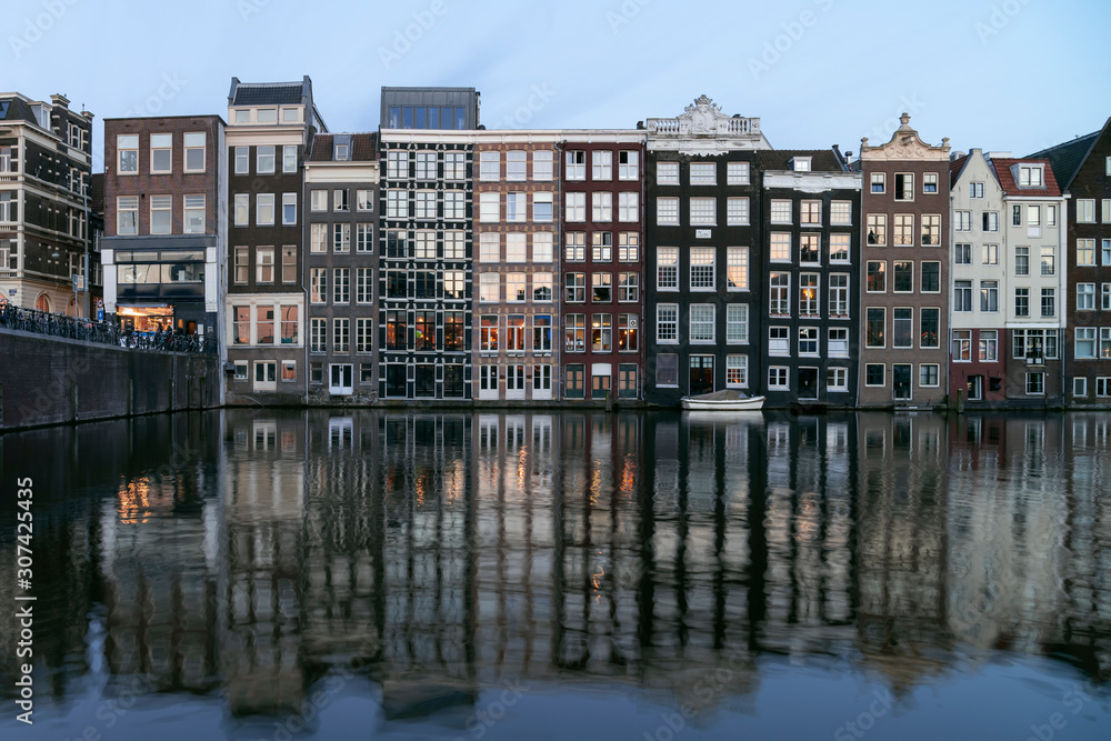 Amsterdam night. Beautiful illuminated Windows in houses on the canal water. Amsterdam canal and skyline at night. Amsterdam city, Netherlands