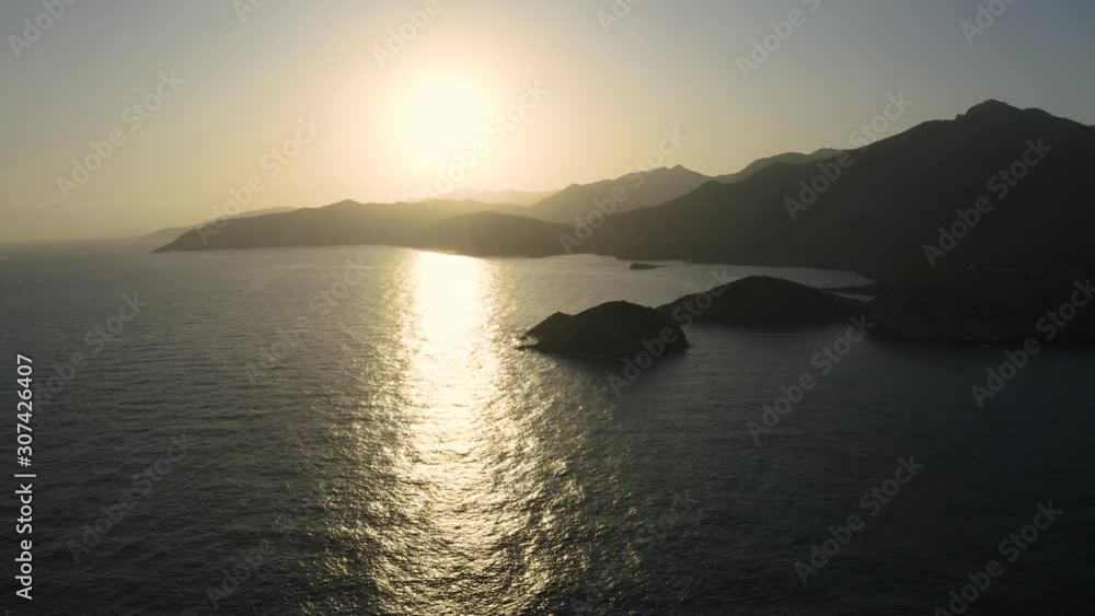 Reflected sun on a water surface at Sunset. Flying above Sea and Mountain in Tenerife Reflected sun on a water surface at Sunset. Flying above Sea and Mountain in Tenerife