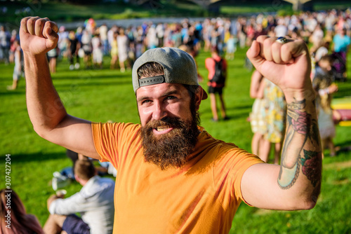 Fan zone. Music festival. Entertainment concept. Visit summer festival. Summer fest. Hipster in cap happy celebrate event fest or festival. Man bearded hipster in front of crowd. Open air concert