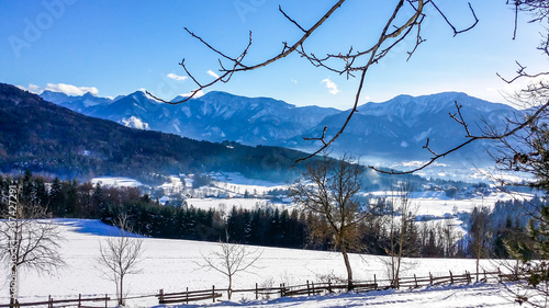 A panoramic view on an alpine winter landscape of Austria. There are high mountain chains in the back. Fresh snow is covering the ground and the trees. Winter wonderland. Crispy day. photo