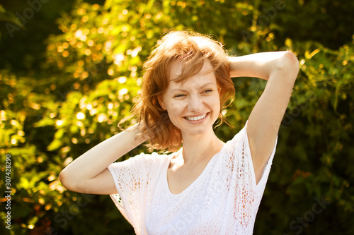 Portrait of happy pretty young woman in park at sunny summer day