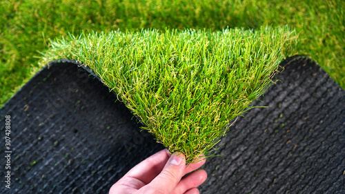 Hand holding an artificial grass roll. Greenering with an artificial turf. © Dmytro
