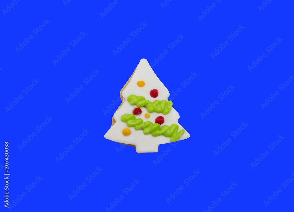 Glazed cookie in form of Christmas tree decorated with colorful frosting on blue background, top view