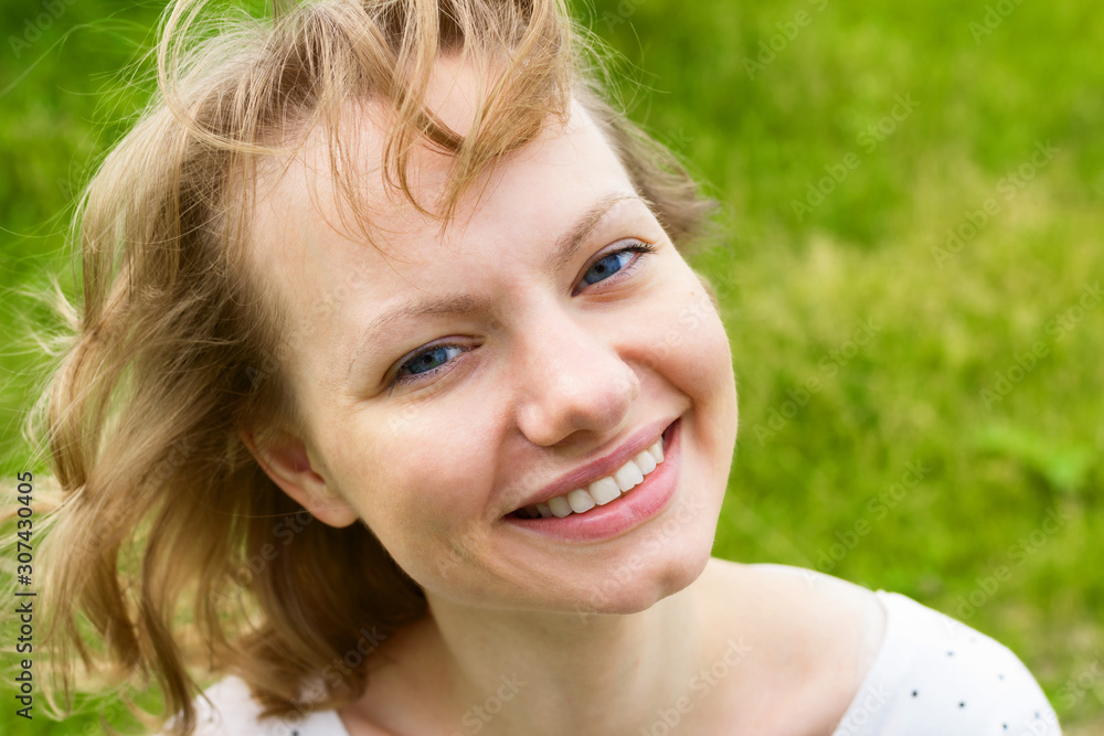 Portrait of happy young woman over green grass background Portrait of happy young woman over green grass background