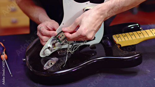 Luthier fixing electrical components of a guitar photo