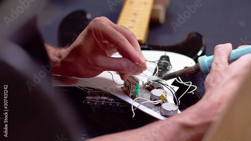 Luthier soldering wires of a broken guitar