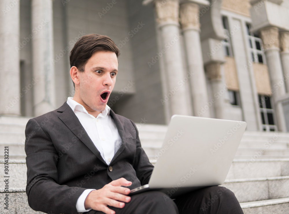 Adult male sitting with face reaction looking at laptop. Adult male sitting with face reaction looking at laptop.