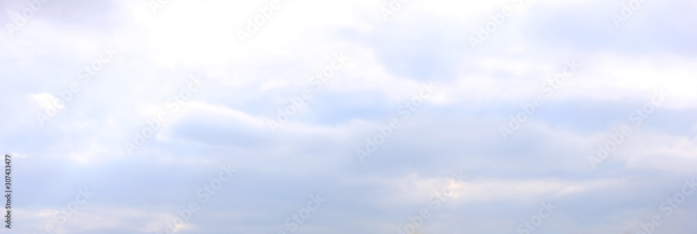 Blue sky cloudy background. Sky texture with fluffy clouds after rain, wide horizontal banner image, weather concept 
