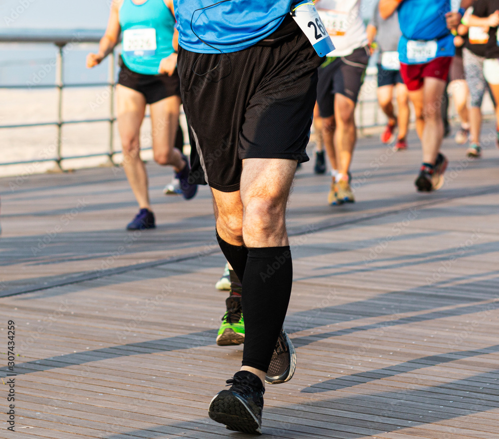Runners legs with compression socks racing on boardwalk by the beach Runners legs with compression socks racing on boardwalk by the beach