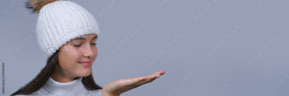 head portrait of happy smiling teen girl holding copyspace on palm isolated on gray background, panorama view.. head portrait of happy smiling teen girl holding copyspace on palm isolated on gray background, panorama view..