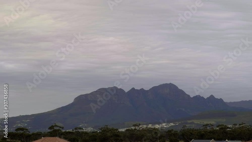 Time lapse of sky filled with light clouds moving swiftly over Helderberg mountain creating a cloud blanket over suburb in distant in 4K.mov photo