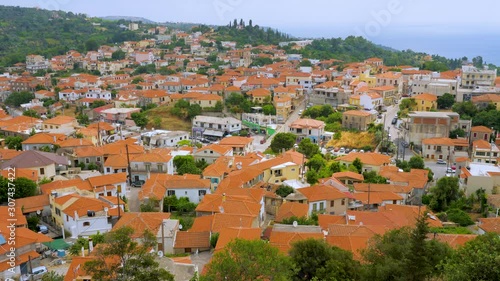 Cityscape with red roofs and mountains on background. Traveling concept. Mountain town, view from the top. Greek cityscape with white houses, red roofs and green trees among houses photo