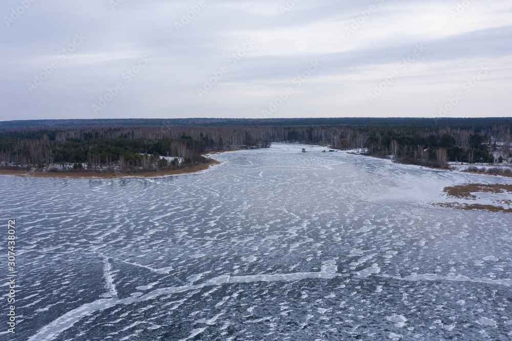 A wide riverbed covered with ice. The view from the top. A wide riverbed covered with ice. The view from the top.