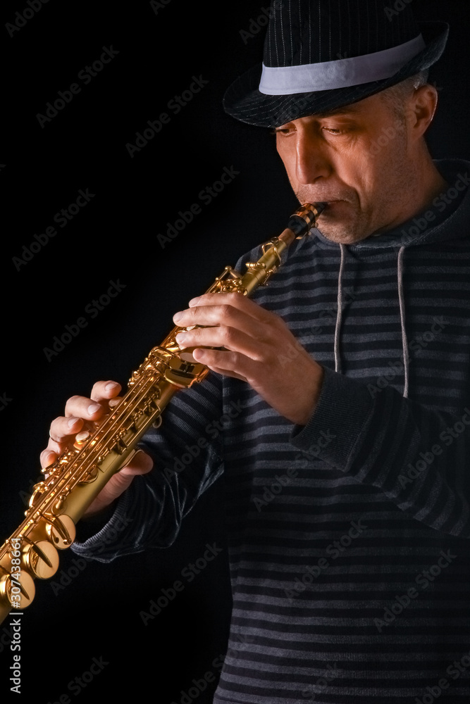 Naklejka premium soprano saxophone in the hands of a guy on a black background