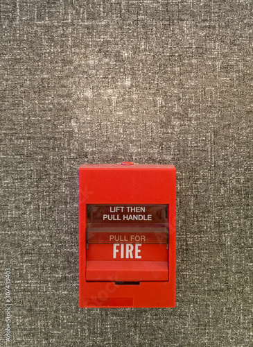 Fire alarm switch on carpet grey wall, Lift then pull handle to alarm, safty system concept, Copyspace and background.