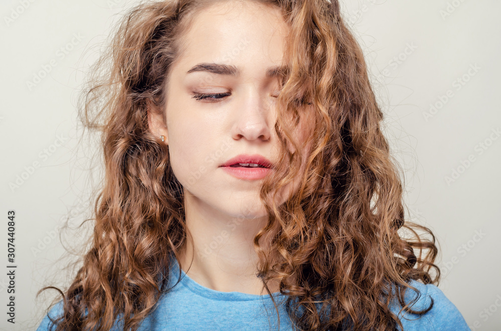 Portrait of beautiful young girl, close-up. Curly hair. Playing hair