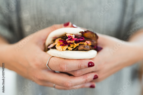 From above of crop hands of woman holding traditional Asian sandwich steamed bun with meat and vegetables photo