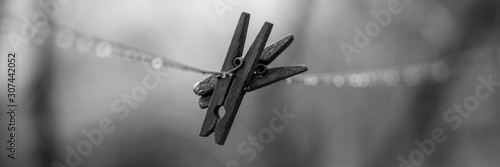 Φωτογραφία Two old wooden clothespins hanging on a clothesline in rainy weather, bw photo