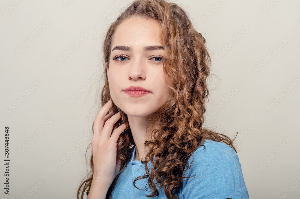 Fototapeta premium Portrait of beautiful young girl, close-up. Curly hair. Playing hair. Seductive smile