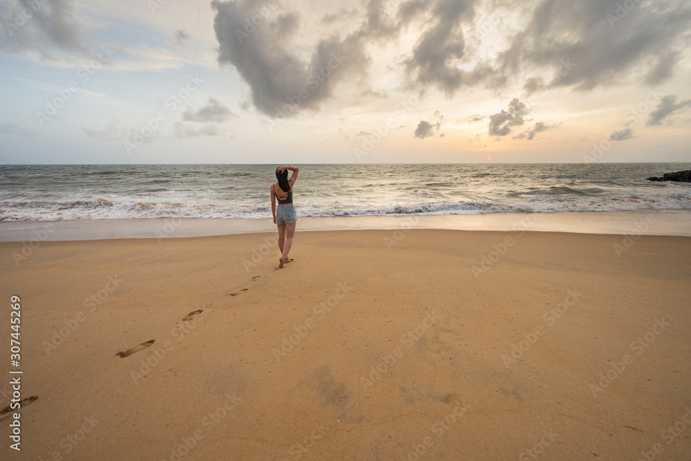 Woman in beachwear walking on sand barefoot Woman in beachwear walking on sand barefoot