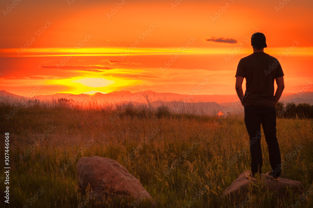 A young person enjoying a sunset over a mountain range