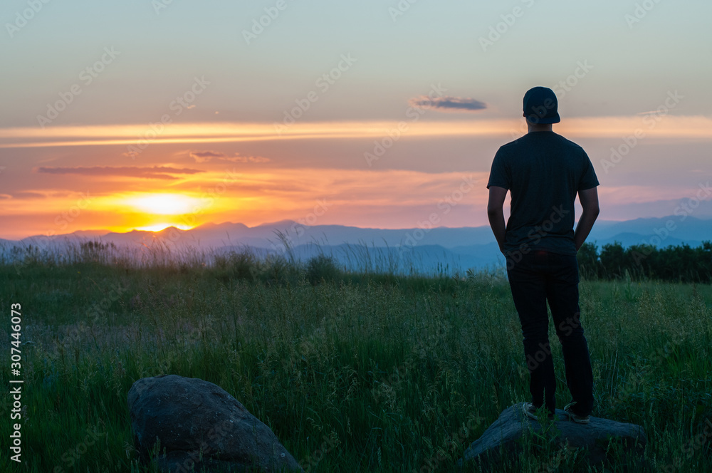 A young person enjoying a sunset over a mountain range