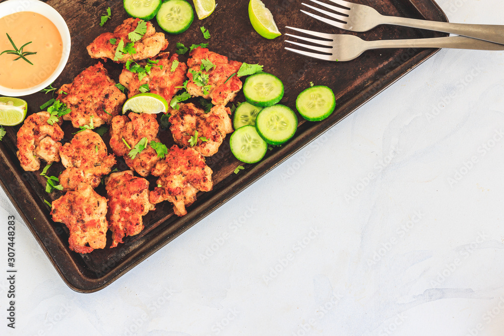 Chicken Fritters on a Dark Baking Tray with Cucumber Slices, Bell Pepper Cubes and Lemon, Garlic Aioli in the Bowl, Top View Food, Negative Space, White Background Chicken Fritters on a Dark Baking Tray with Cucumber Slices, Bell Pepper Cubes and Lemon, Garlic Aioli in the Bowl, Top View Food, Negative Space, White Background