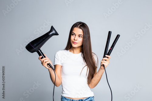 Young pretty woman holding hair dryer and straightening isolated on white background