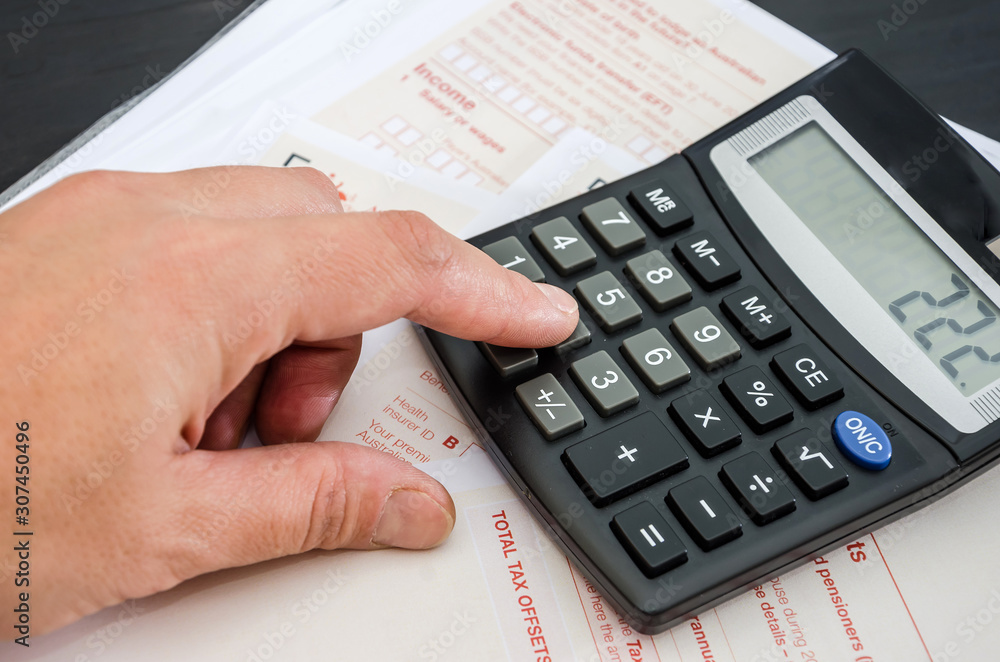 hand prints something on a calculator against the background of tax forms hand prints something on a calculator against the background of tax forms