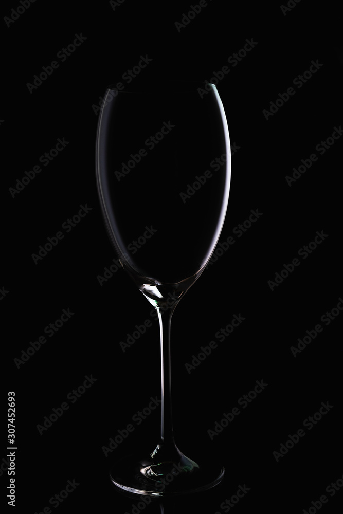 Glass goblet without wine on a thin leg stands on a mirror surface.