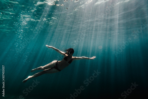 Low angle view of woman swimming underwater in ocean photo