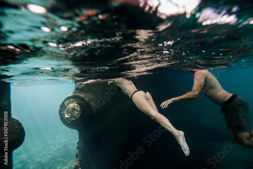 Couple swimming underwater close to old boat photo