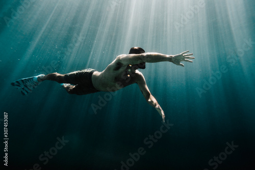 Low angle view of man swimming underwater in ocean photo