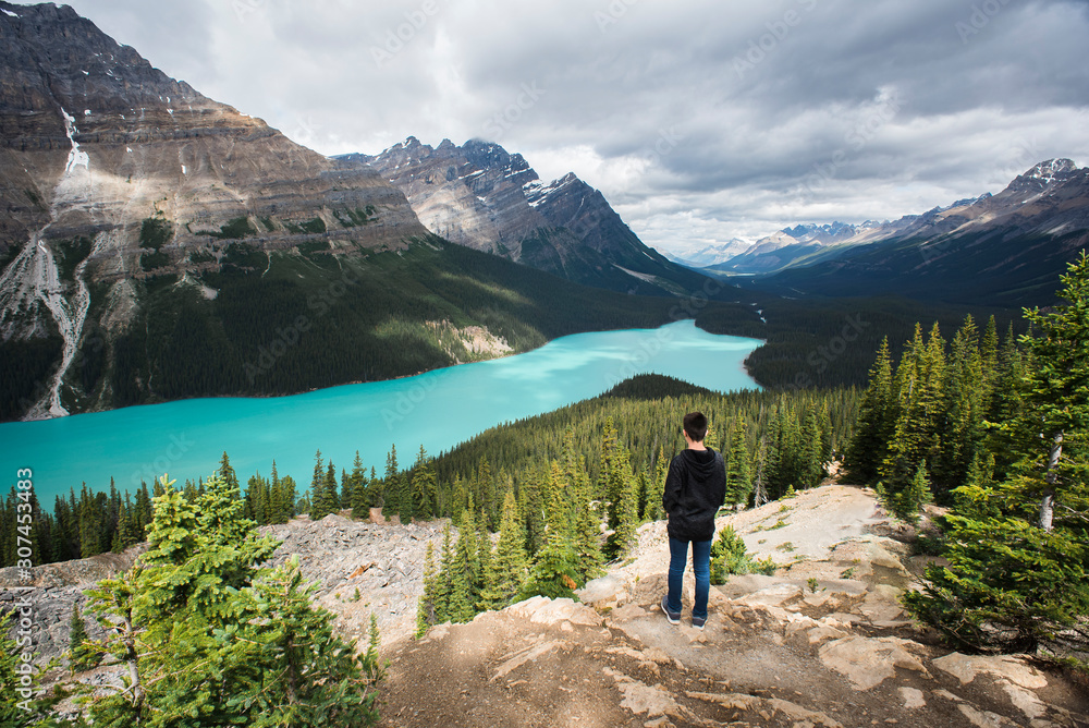 Teenage boy standing on rocks looking at Peyto Lake in the Rockies. Teenage boy standing on rocks looking at Peyto Lake in the Rockies.