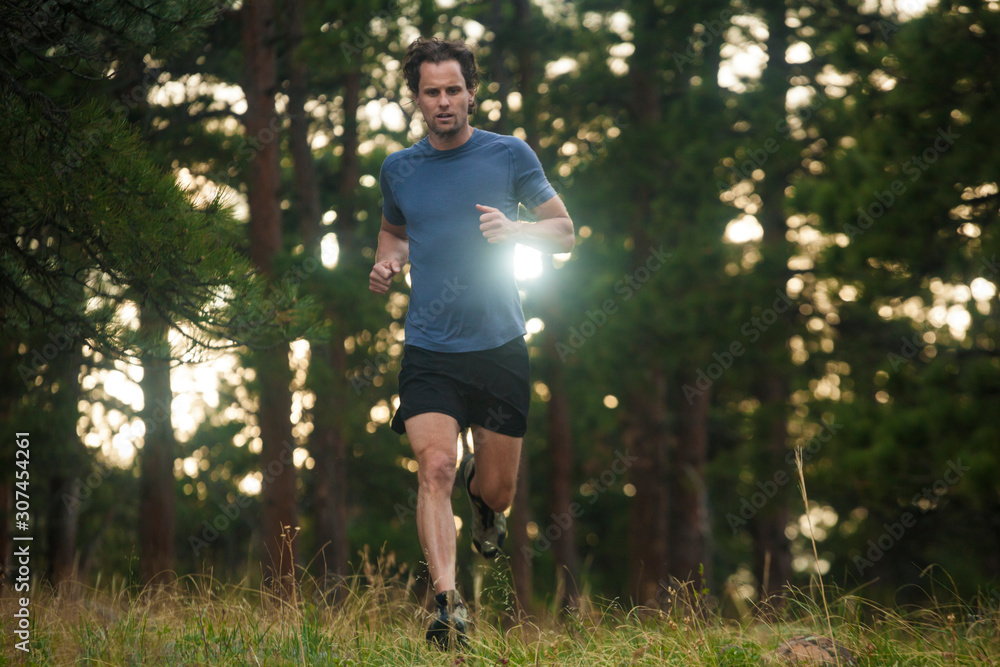 Man runs backlit through forest in Chautauqua above Boulder, Colorado Man runs backlit through forest in Chautauqua above Boulder, Colorado
