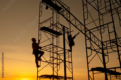 Silhouette construction worker Climbing scaffolding In order to go up to check the work site