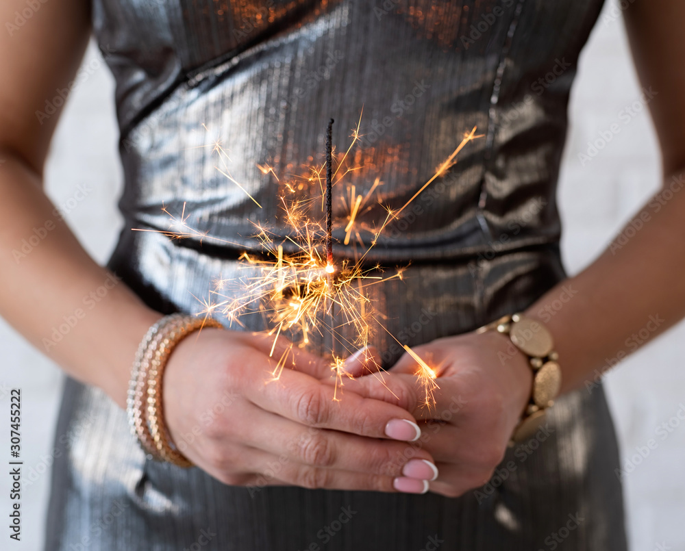 Woman in a party dress holding a sparkler in her hands Woman in a party dress holding a sparkler in her hands