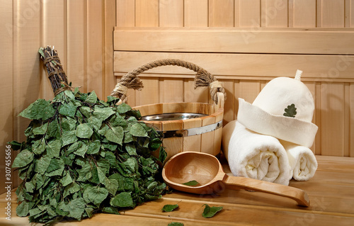 Birch broom and a wooden bucket in a Russian bath close-up, bath accessories.