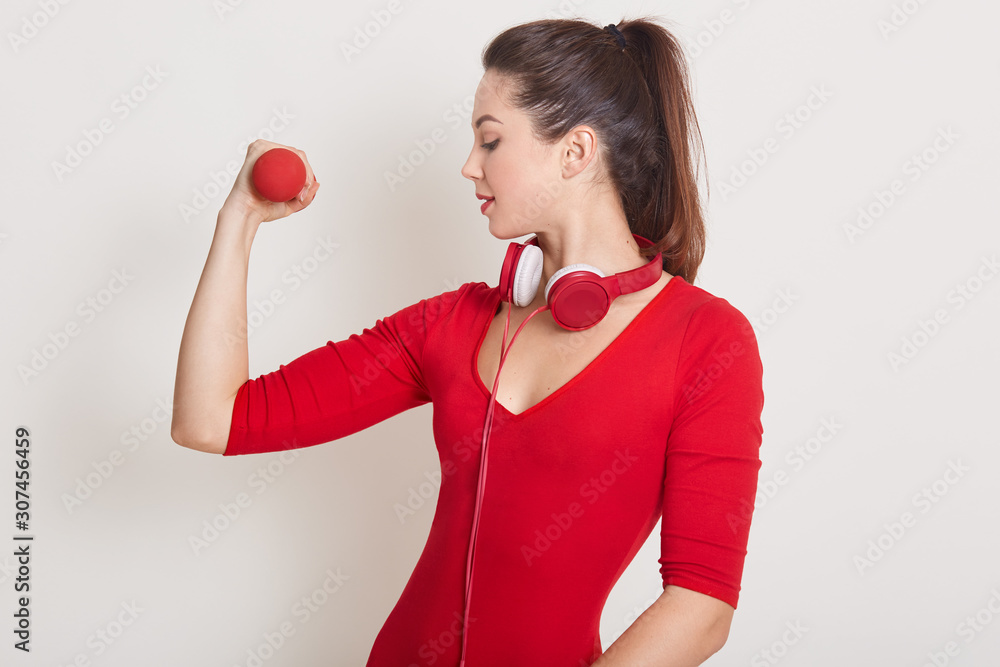 Studio shot of healthy Caucasian woman with dumbbells working out isolated over white background. Attrractive lady showing her mascles, looking on her arm, Fitness, gym, healthy care concept. Studio shot of healthy Caucasian woman with dumbbells working out isolated over white background. Attrractive lady showing her mascles, looking on her arm, Fitness, gym, healthy care concept.