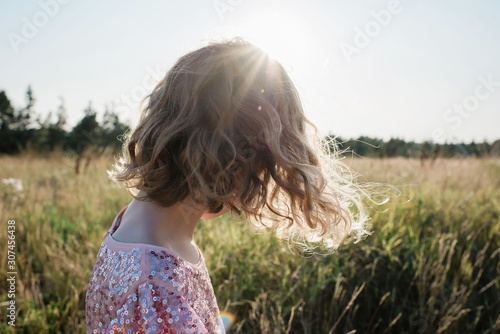 portrait of the back of a girl walking at sunset in a sparkly dress photo