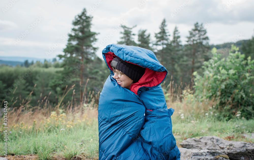 portrait of a woman wrapped in a sleeping bag whilst camping outdoors portrait of a woman wrapped in a sleeping bag whilst camping outdoors