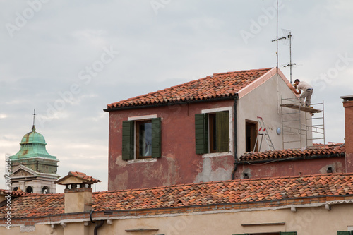 Worker doing a repair on the roofs of Venice on a cloudy day