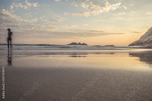 Boy in the sea shore during sunset at Joatinga beach photo