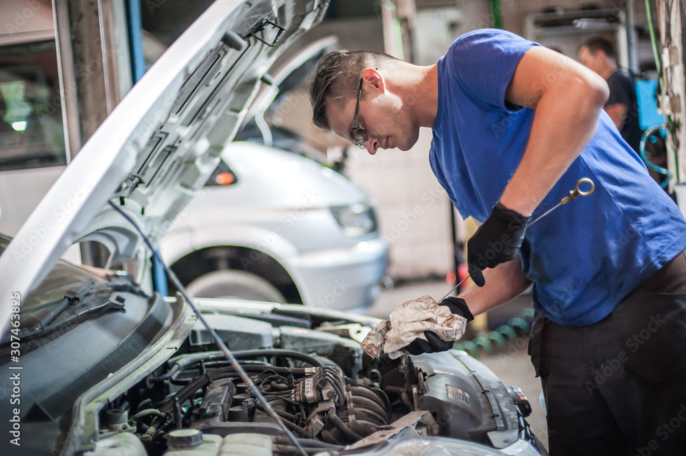 Auto mechanic repairer checking level of oil in car engine Auto mechanic repairer checking level of oil in car engine