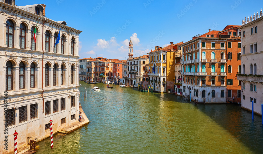 Venice, Italy. Gondolas on Grand Canal among antique buildings and traditional italian Venetian architecture. Sunny day with blue sky and clouds. Venice, Italy. Gondolas on Grand Canal among antique buildings and traditional italian Venetian architecture. Sunny day with blue sky and clouds.