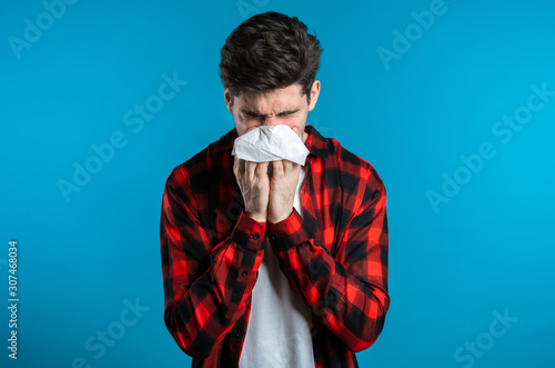 Photos Young man sneezes into tissue